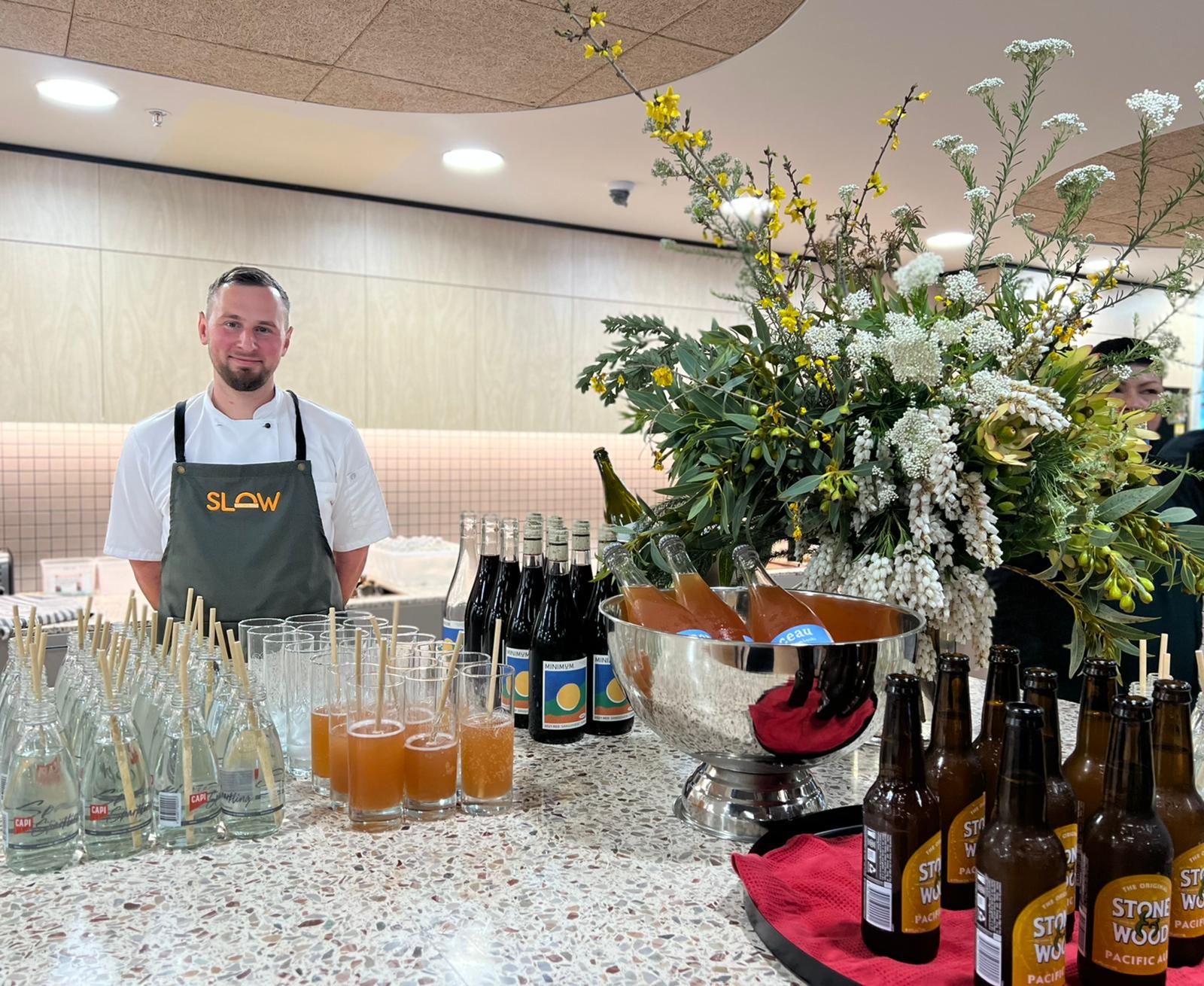 chase the owner of slow food standing behind the bar featuring minimum wines, stone and wood beer, capi water and monceau kombucha the Bank Australian new office launch of 2022 at 54 wellington st collingwood