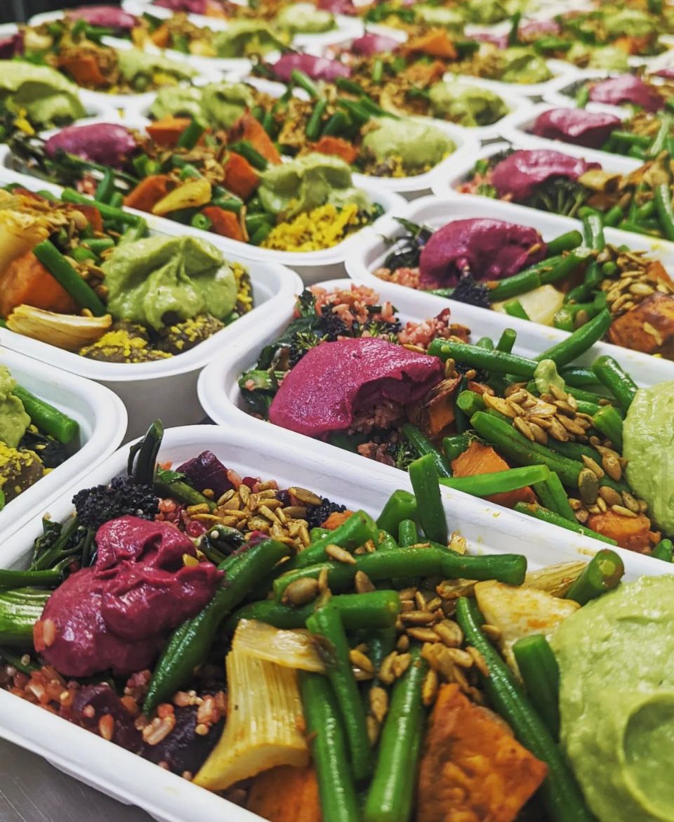 multiple meals lined up in home compostable packaging. Vibrant green avocado sauce, sassy pink beetroot, white bean and sumac sauce, crisp green beans, roasted fennel & sweet potato on Australian biodynamic brown rice and garnished with organic turmeric seeds