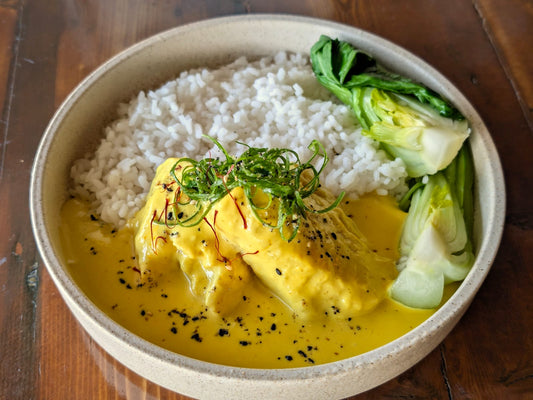 Bowl of food with rice, egg, and greens on a wooden surface